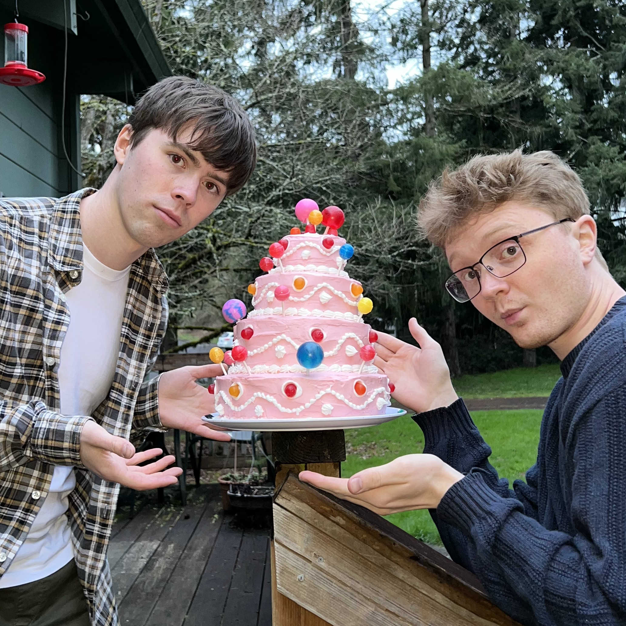 Two people presenting a large pink cake.